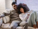 beloved african american couple cuddling and smiling on couch